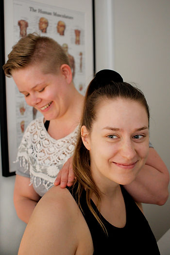 Hoitotilannekuva, osteopaatti on istuvan asiakkaan selän takana. Osteopaatti ja asiakas hymyilevät.
