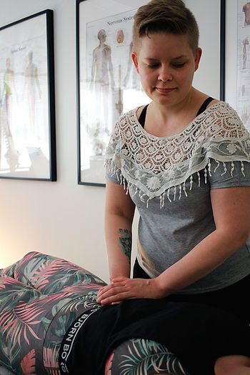 Hoitotilanne, osteopaatin kädet ovat asiakkaan lantion päällä. 